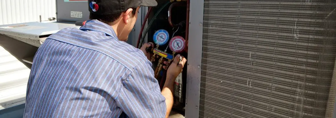 HVAC technician servicing a condenser unit in Bensville