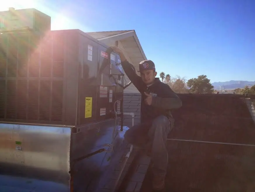 HVAC technician performing AC Tune-Up on a rooftop unit in Bensville